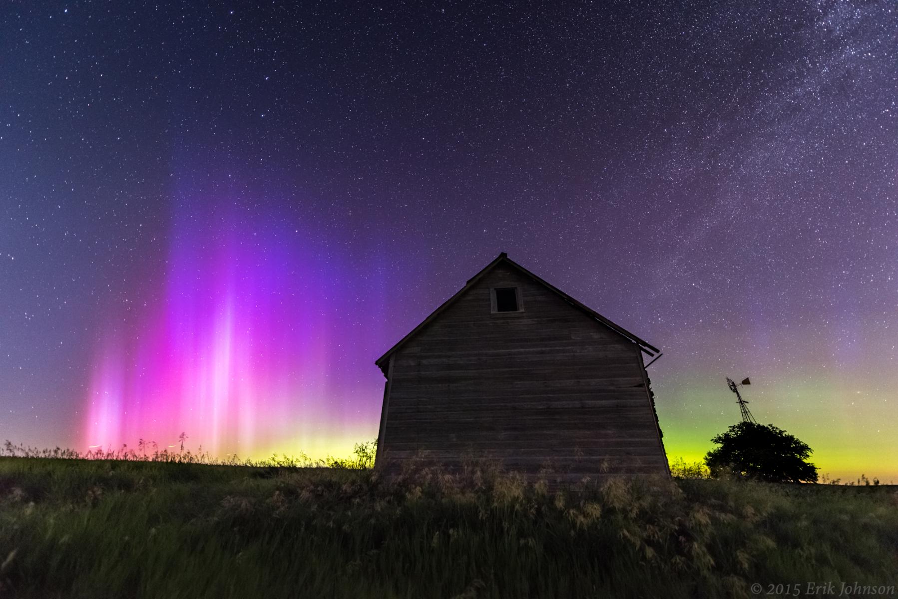 Aurora Borealis in the sky behind a wooden barn