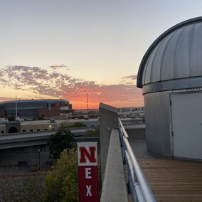 University of Nebraska Student Observatory telescope dome with light clouds and red sunset in the background.